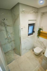 a bathroom with a shower and a toilet and a television at Apartmani LE-LU in Kaštela +55 photos