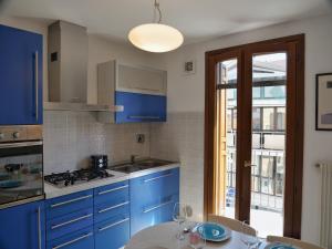 een keuken met blauwe kasten en een tafel met wijnglazen bij Lounge Del Duca, centralissimo bicamere su due livelli - posto auto a richesta in Grado