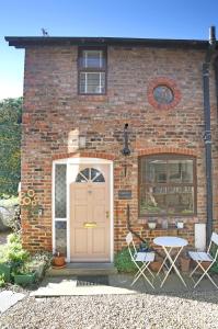 uma casa de tijolos com uma porta rosa e uma mesa em Thirsk Stays - Bakery Cottage em Thirsk