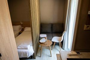 Habitación pequeña con cama, mesa y espejo. en CAMPING RESORT LA TRAPERA, en Pradoluengo