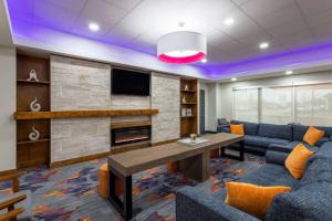 a living room with a couch and a table and a tv at La Quinta Inn & Suites by Wyndham Augusta Fort Eisenhower in Augusta