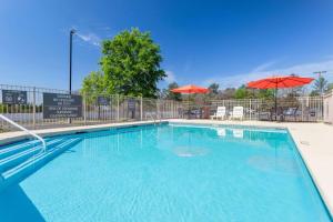 een groot zwembad met twee parasols en stoelen bij La Quinta Inn & Suites by Wyndham Augusta Fort Eisenhower in Augusta