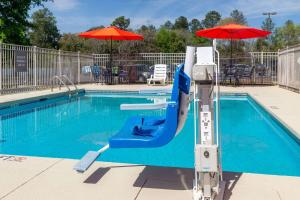 a swimming pool with a slide and an umbrella at La Quinta Inn & Suites by Wyndham Augusta Fort Eisenhower in Augusta