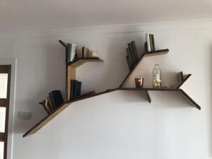 uma prateleira na parede com livros e uma garrafa. em ' High Tor House, a taste of paradise on Harris ' em Tarbert