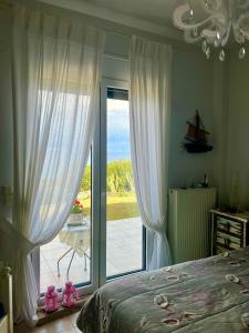Schlafzimmer mit einem Bett und einer Glasschiebetür in der Unterkunft Aegean Pearl in Posidi