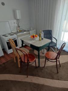 una cocina con mesa, sillas y una mesa con fruta. en Apartman Bor, en Livno