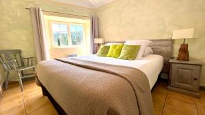Un dormitorio con una cama con almohadas verdes y una ventana en Logis Hôtel Restaurant Le Domaine de l'Eau Vive en Largentière