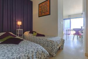 two beds in a hotel room with purple curtains at French Riviera 1 bedroom on the beach facing Cannes in Théoule-sur-Mer