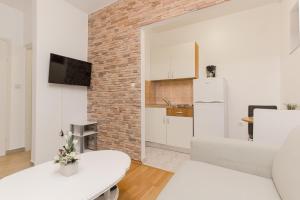 uma sala de estar com um sofá branco e uma parede de tijolos em Apartments Maky & Dino em Vodice