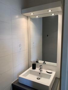 een witte badkamer met een wastafel en een spiegel bij Appartement 4 personnes in Narbonne