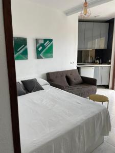 a bedroom with a white bed and a couch at Calle Manuel Mena 4 in Arroyo de la Miel