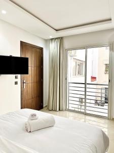 a white bedroom with a large bed and a large window at MyCity in Rabat