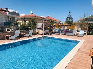 a swimming pool with chairs and a house at Fizzio Alaçatı Hotel in Alaçatı