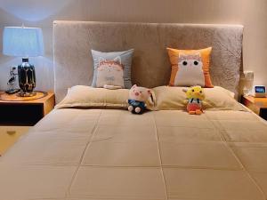 una cama con tres animales de peluche sentados en ella en 舟山朱家尖东沙绿城品霞苑酒店式公寓 en Zhoushan