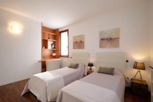 ガルダにあるApartmentsGarda - GardaLux Apartmentsの白い壁の客室内のベッド2台