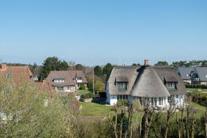 une maison au toit de chaume dans un village dans l'établissement Syltdomizil Westsuite, à Wenningstedt