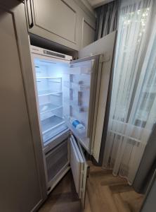 an empty refrigerator with its door open in a room at 2-комн на Молдагулова in Shymkent