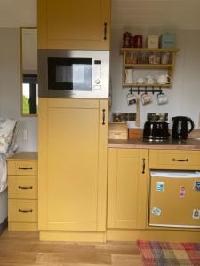 una cucina con forno a microonde sopra un armadio giallo di Atlantic Way Shepherd Hut a Moville