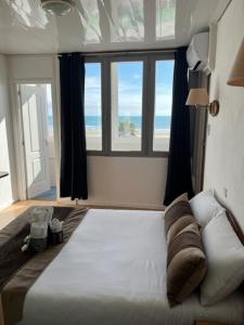 a bedroom with a bed and a large window at Le Mazagan in Port-la-Nouvelle