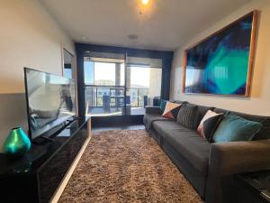 a living room with a couch and a flat screen tv at Midnight Luxe 2BR 2Bath Executive Apartment in the heart of Braddon Pool Sauna Views Secure Parking Wine WiFi in Canberra
