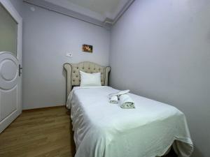a bedroom with a bed with white sheets and shoes on it at İSTANBLUE TAKSİM APART HOTEL in Istanbul