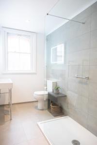uma casa de banho com uma cabina de duche em vidro e um WC. em Spacious 1BR Victorian Cheltenham flat in Cotswolds Sleeps 4 - FREE Parking em Cheltenham