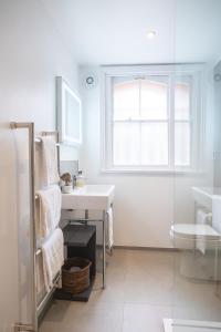 a white bathroom with a sink and a window at Spacious 1BR Victorian Cheltenham flat in Cotswolds Sleeps 4 - FREE Parking in Cheltenham
