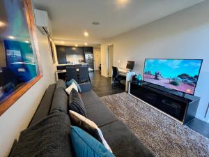 a living room with a couch and a flat screen tv at Midnight Luxe 2BR 2Bath Executive Apartment in the heart of Braddon Pool Sauna L4 Views Secure Parking Wine WiFi in Canberra