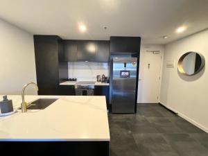 a kitchen with a refrigerator and a counter top at Midnight Luxe 2BR 2Bath Executive Apartment in the heart of Braddon Pool Sauna L4 Views Secure Parking Wine WiFi in Canberra
