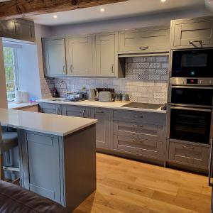 a kitchen with white cabinets and a stove top oven at 1 Bridge Syke Elterwater in Ambleside