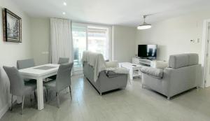 een woonkamer met een tafel en stoelen en een televisie bij Dunas de Marivilla by Spain2home in Torrox
