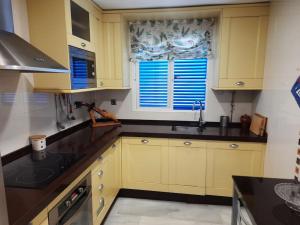 uma cozinha com armários amarelos e um lavatório em Amplio apartamento en La Barrosa em Novo Sancti Petri