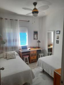 a bedroom with two beds and a desk with a laptop at Amplio apartamento en La Barrosa in Novo Sancti Petri