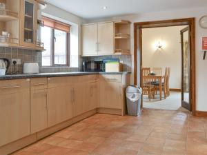 a kitchen with wooden cabinets and a dining room at Dairy Cottage - Ukc3735 in Bawdeswell