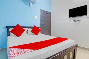 - une chambre avec un lit doté d'oreillers rouges et une télévision dans l'établissement OYO Flagship Hanuma Residencies, à Hyderabad