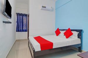 - une chambre avec un lit doté d'oreillers rouges et une télévision dans l'établissement OYO Flagship Hanuma Residencies, à Hyderabad