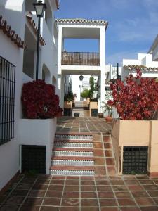 um pátio de uma casa com escadas e flores vermelhas em Playa Golf em Benalmádena