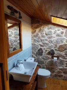 baño con lavabo y pared de piedra en Casa Andrés Quilmas, en Carnota