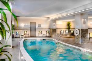 una piscina en una habitación de hotel con sillas y mesas en Residence Inn by Marriott Charlottesville Downtown, en Charlottesville