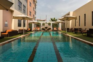 una piscina en un hotel con mesas y sombrillas en Protea Hotel by Marriott Ikeja Select, en Ikeja