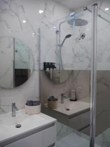 a bathroom with a shower and two sinks and a mirror at Cocon lumineux avec parking et sauna Paris direct in Asnières-sur-Seine