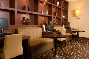 a hotel room with a waiting area with tables and chairs at Courtyard Los Angeles Sherman Oaks in Sherman Oaks