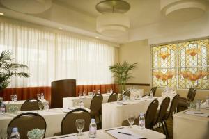 un restaurante con mesas y sillas blancas y vidrieras en Courtyard Los Angeles Sherman Oaks en Sherman Oaks