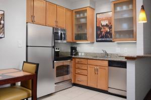 uma cozinha com utensílios de aço inoxidável e armários de madeira em Residence Inn by Marriott Dallas Plano The Colony em The Colony