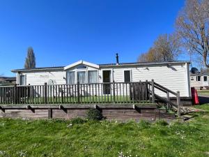 Casa blanca pequeña con terraza de madera en Meridian Lodge en Great Billing