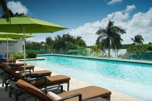 a swimming pool with chairs and an umbrella at The Westin Cancun Resort Villas & Spa in Cancún