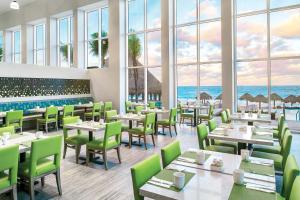 a restaurant with tables and chairs with the ocean in the background at The Westin Cancun Resort Villas & Spa in Cancún