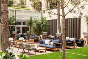 patio z niebieskimi kanapami, krzesłami i drzewami w obiekcie Renaissance Bordeaux Hotel w mieście Bordeaux