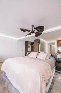 1 dormitorio con 1 cama blanca y ventilador de techo en Loft 7 piso frente al mar para 2 personas en Monte Hermoso