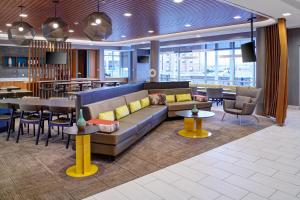 a lobby with a couch and tables and a restaurant at SpringHill Suites by Marriott Detroit Wixom in Wixom
